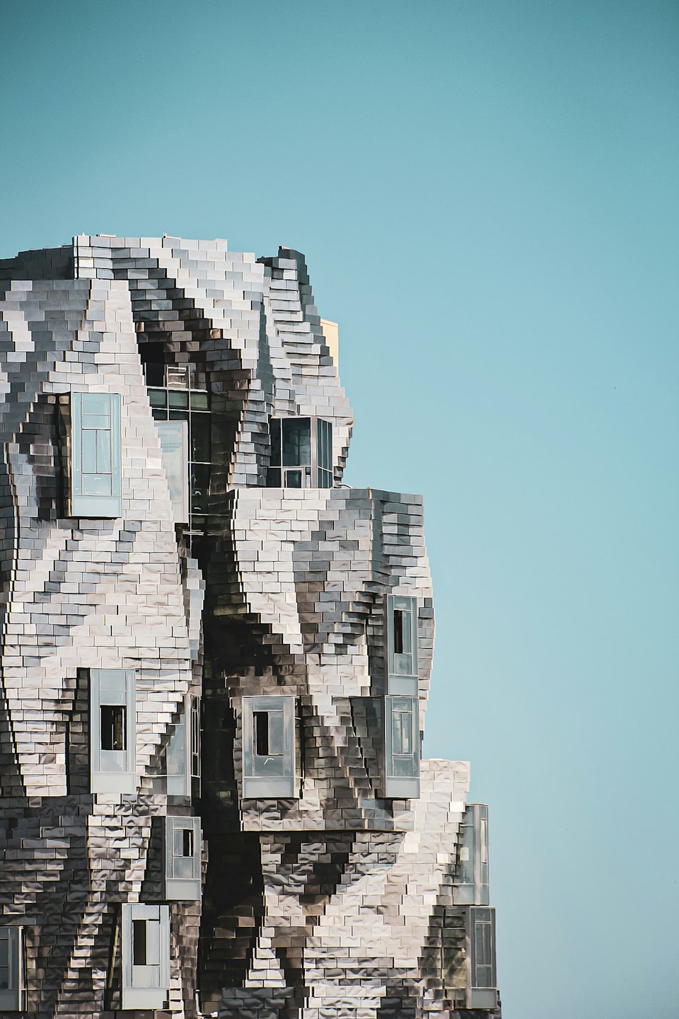 Edificio moderno con facciata metallica ondulata e testurizzata e finestre rettangolari.