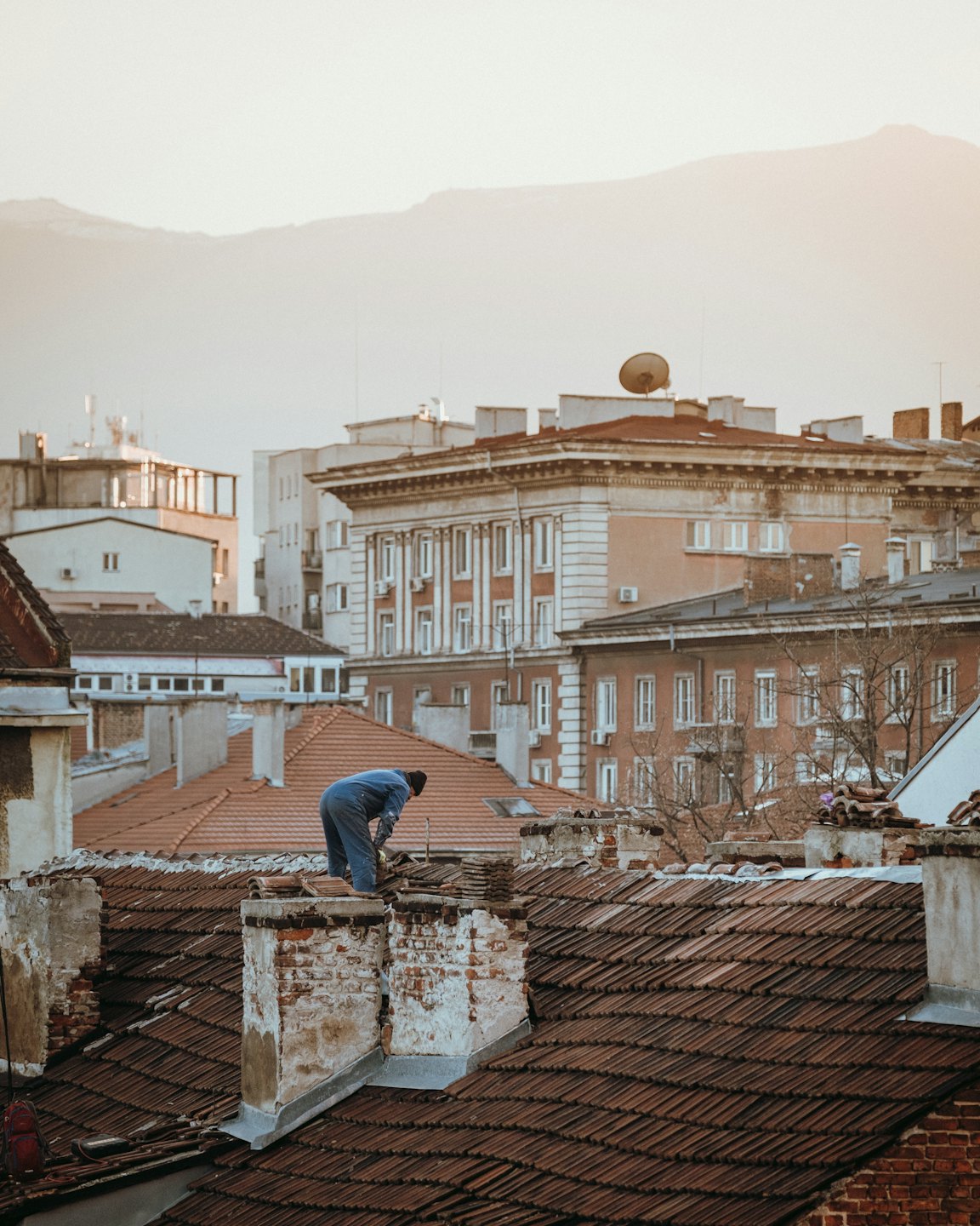 Operaio edile ripara tetto in cotto antico in città storica.
