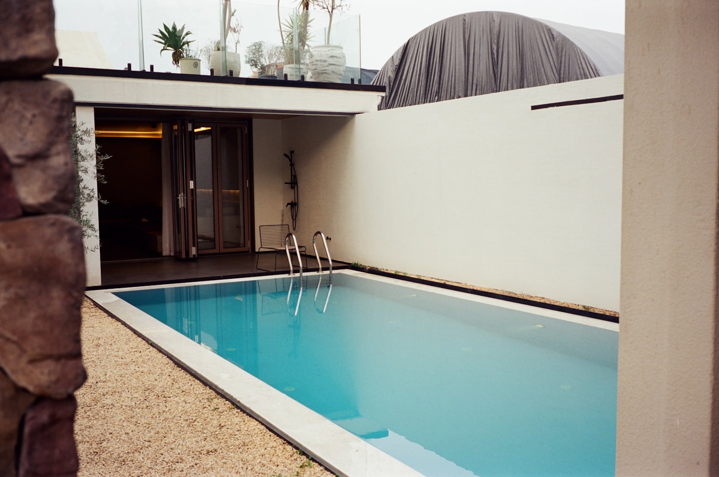 Piscina moderna con pareti bianche e zona patio.